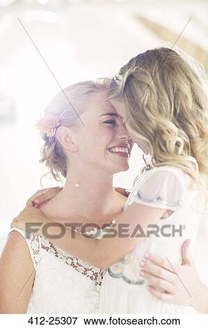 Stock Photo - Bride holding bridesmaid in domestic room. Fotosearch