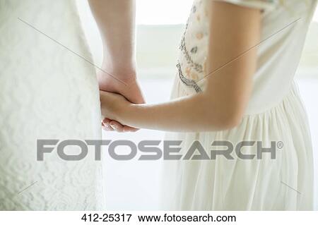Bride holding bridesmaid's hand in domestic room View Large Photo Image Stock Photo - Bride holding bridesmaid's hand in domestic room. Fotosearch