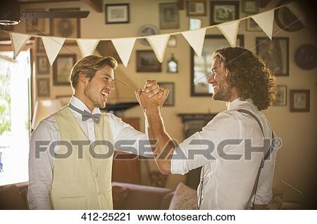Bridegroom and best man holding hands in domestic room View Large Photo Image Stock Image - Bridegroom and best man holding hands in domestic room. Fotosearch