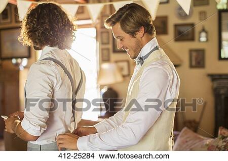 Picture - Bridegroom and best man preparing for wedding ceremony in domestic room. Fotosearch
