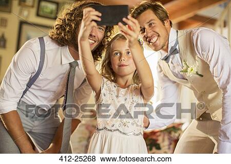 Stock Photo - "Bridegroom, best man and bridesmaid photographing self in domestic room". Fotosearch
