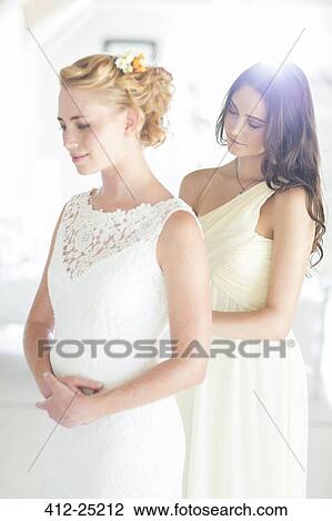 Bridesmaid helping bride with dressing in bedroom View Large Photo Image Stock Image - Bridesmaid helping bride with dressing in bedroom. Fotosearch