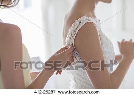 Bridesmaid helping bride with dressing in domestic room View Large Photo Image Stock Photo - Bridesmaid helping bride with dressing in domestic room. Fotosearch