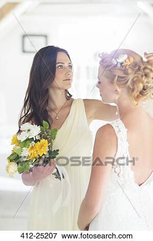 Bridesmaid helping bride with hairstyle in bedroom View Large Photo Image Stock Photo - Bridesmaid helping bride with hairstyle in bedroom. Fotosearch