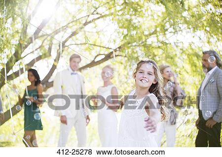 Stock Photo - Bridesmaid playing with bubbles at wedding reception in domestic garden. Fotosearch