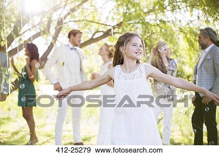 Stock Photo - Bridesmaid playing with bubbles at wedding reception in domestic garden. Fotosearch