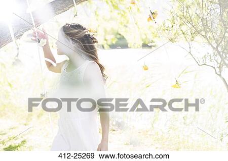 Stock Photo - Bridesmaid playing with decorations in domestic garden during wedding reception. Fotosearch