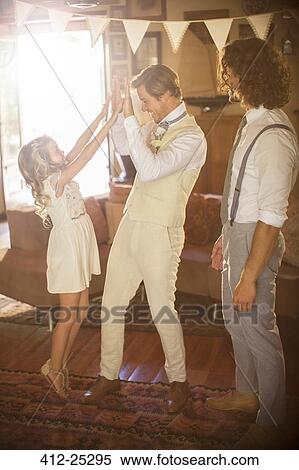 Groom and bridesmaid high fiving in domestic room View Large Photo Image Stock Photography - Groom and bridesmaid high fiving in domestic room. Fotosearch
