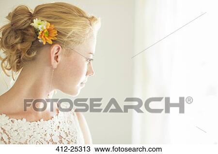 Stock Image - Portrait of bride looking out of window. Fotosearch