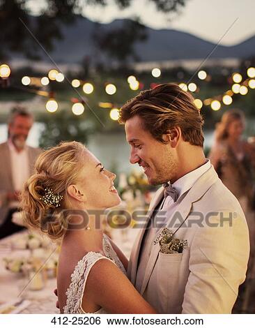 Stock Photograph - Portrait of young couple dancing in garden during wedding reception. Fotosearch