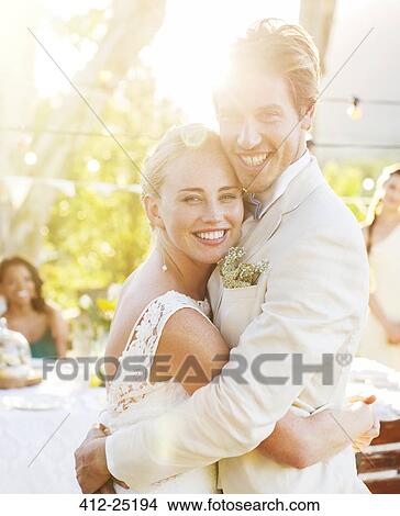 Picture - Portrait of young couple embracing in garden during wedding reception. Fotosearch