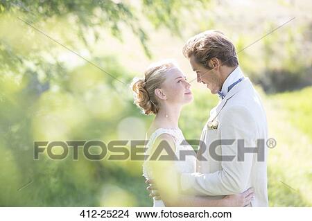 Picture - Portrait of young couple embracing in domestic garden. Fotosearch