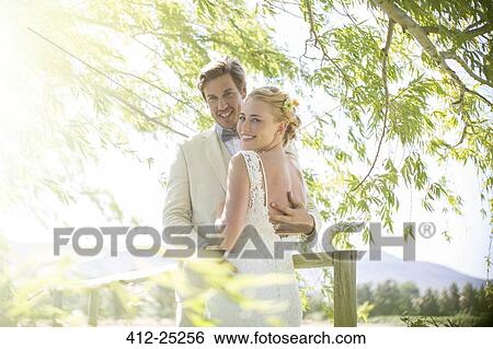 Portrait of young couple embracing on wooden bridge View Large Photo Image Stock Photograph - Portrait of young couple embracing on wooden bridge. Fotosearch