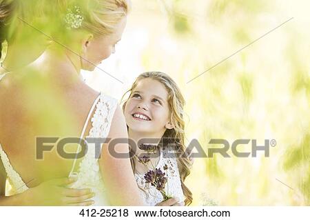 Stock Photo - Smiling bridesmaid with flowers and bride during wedding reception in garden. Fotosearch