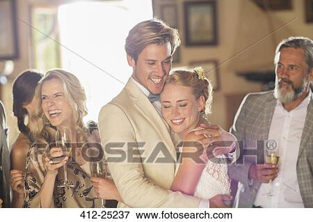 Stock Photo - Young couple and guests at wedding reception in domestic room. Fotosearch