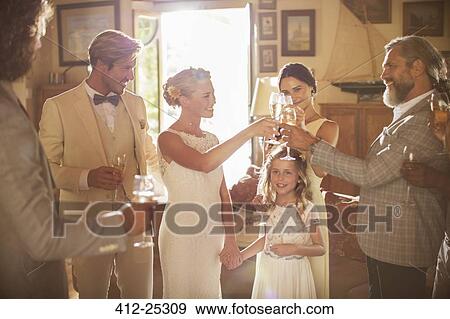 Young couple and guests toasting with champagne during wedding reception in domestic room View Large Photo Image Stock Photo - Young couple and guests toasting with champagne during wedding reception in domestic room. Fotosearch