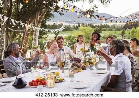 Young couple and their guests sitting at table during wedding reception in garden View Large Photo Image Stock Image - Young couple and their guests sitting at table during wedding reception in garden. Fotosearch