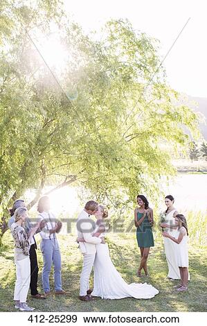Young couple embracing and kissing during wedding ceremony in domestic garden View Large Photo Image Stock Photo - Young couple embracing and kissing during wedding ceremony in domestic garden. Fotosearch