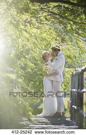 Young couple embracing on wooden bridge View Large Photo Image Stock Image - Young couple embracing on wooden bridge. Fotosearch