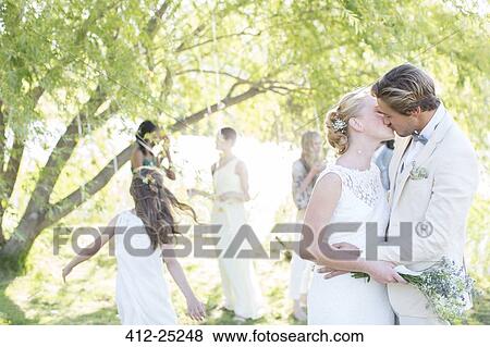 Young couple kissing at wedding reception in domestic garden View Large Photo Image Stock Photo - Young couple kissing at wedding reception in domestic garden. Fotosearch