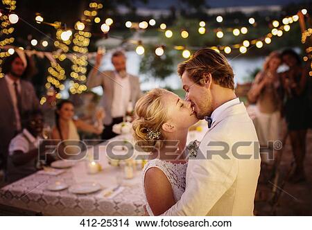 Young couple kissing during wedding reception in domestic garden View Large Photo Image Picture - Young couple kissing during wedding reception in domestic garden. Fotosearch