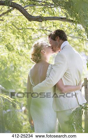 Young couple kissing in domestic garden View Large Photo Image Picture - Young couple kissing in domestic garden. Fotosearch