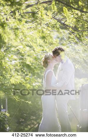Young couple kissing in domestic garden View Large Photo Image Picture - Young couple kissing in domestic garden. Fotosearch