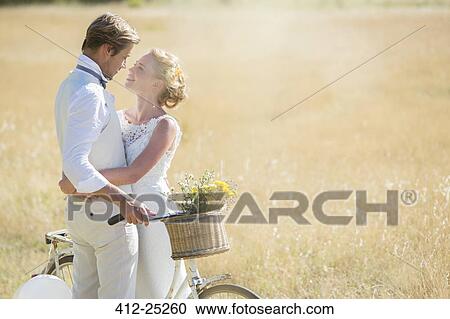 Young couple with bike in meadow View Large Photo Image Stock Image - Young couple with bike in meadow. Fotosearch