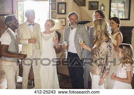 Stock Image - Young couple with guests and champagne flutes at wedding reception. Fotosearch