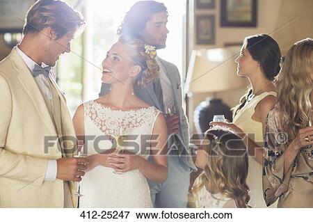 Stock Photo - Young couple with guests and champagne flutes at wedding reception. Fotosearch