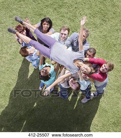 Stock Photo - Carefree woman crowdsurfing supported by team. Fotosearch