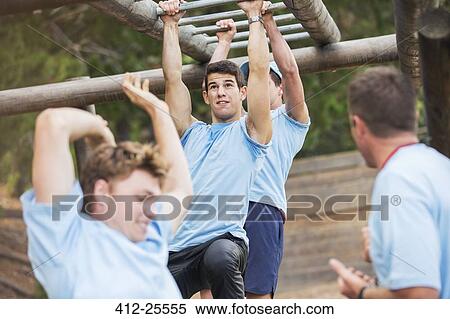 Determined man swinging on monkey bars on boot camp obstacle course View Large Photo Image Stock Photography - Determined man swinging on monkey bars on boot camp obstacle course. Fotosearch