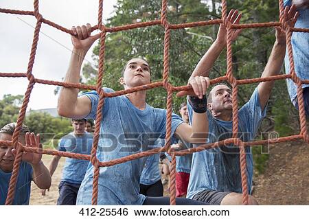 Determined woman climbing net at boot camp obstacle course View Large Photo Image Stock Photograph - Determined woman climbing net at boot camp obstacle course. Fotosearch