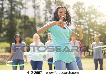 Stock Image - Enthusiastic woman spinning in plastic hoop. Fotosearch