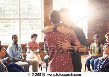 Stock Photo - Men hugging at group therapy session. Fotosearch