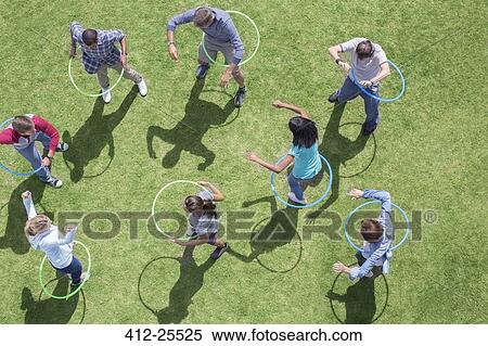 Stock Photography - People spinning in plastic hoops in sunny grass. Fotosearch