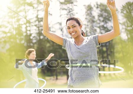 Stock Image - Portrait of smiling woman spinning in plastic hoop. Fotosearch