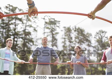 Stock Image - Team connected in circle around plastic hoop. Fotosearch