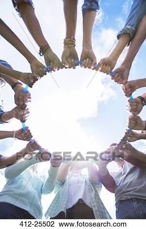 Team forming connected circle around plastic hoop View Large Photo Image Stock Image - Team forming connected circle around plastic hoop. Fotosearch
