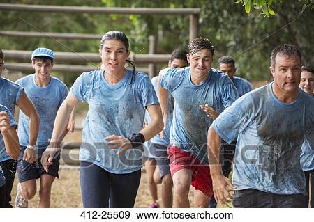 Stock Photo - Team running in rain on boot camp obstacle course. Fotosearch