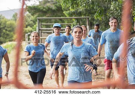 Stock Photograph - Team running in rain on boot camp obstacle course. Fotosearch