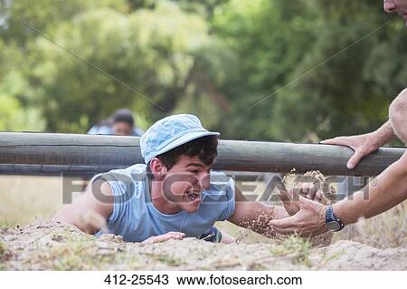 Teammate helping man crawling on boot camp obstacle course View Large Photo Image Stock Image - Teammate helping man crawling on boot camp obstacle course. Fotosearch