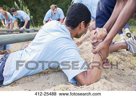 Stock Photo - Teammate helping man on boot camp course. Fotosearch