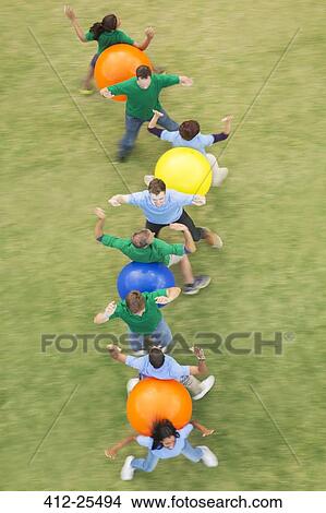 Teammates performing fitness ball team building activity View Large Photo Image Picture - Teammates performing fitness ball team building activity. Fotosearch