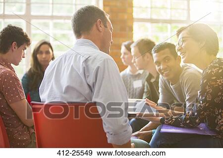 Woman with digital tablet speaking to man at group therapy session View Large Photo Image Stock Photo - Woman with digital tablet speaking to man at group therapy session. Fotosearch