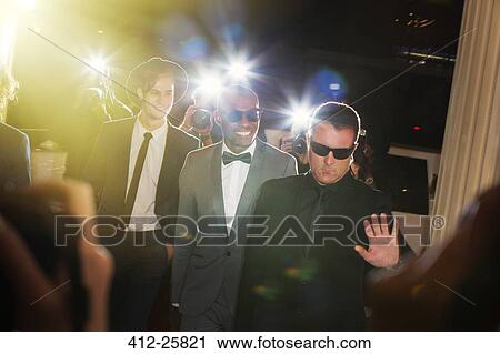 Bodyguard escorting celebrities arriving at event and being photographed by paparazzi View Large Photo Image Stock Image - Bodyguard escorting celebrities arriving at event and being photographed by paparazzi. Fotosearch