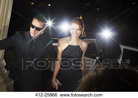 Stock Photograph - Bodyguard escorting smiling celebrity arriving at event. Fotosearch