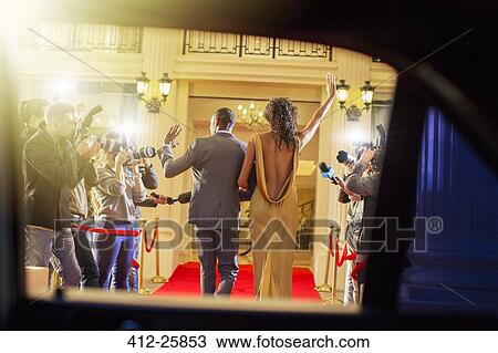 Celebrity couple arriving and waving to paparazzi photographers at red carpet event View Large Photo Image Stock Image - Celebrity couple arriving and waving to paparazzi photographers at red carpet event. Fotosearch