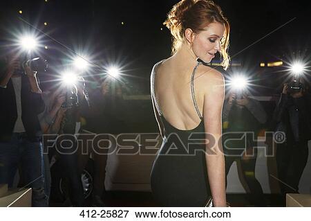 Stock Photo - Celebrity in black dress being photographed by paparazzi photographers. Fotosearch
