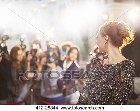 Picture - Celebrity turning and smiling at paparazzi photographers at event. Fotosearch